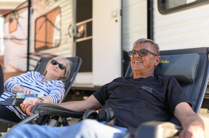 Photo of a man and woman sitting in chairs in front of an RV