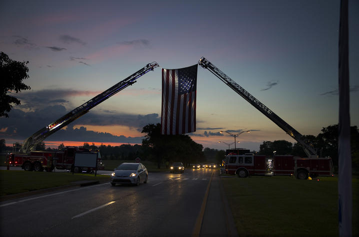 Photo of a massive American flag hanging between two Lexington Fire Department trucks