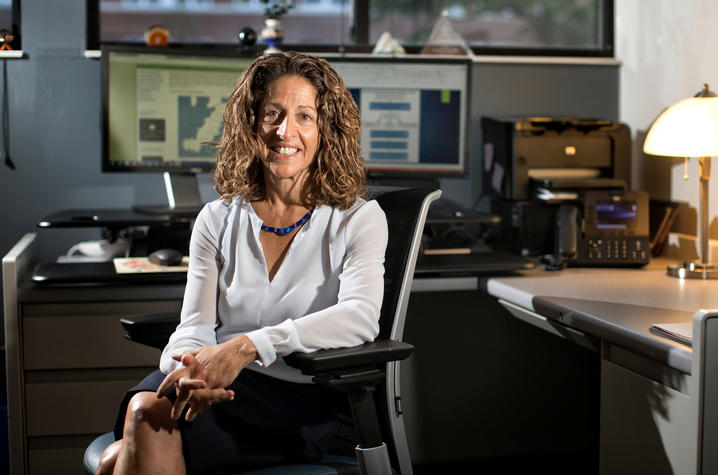 Woman in blouse sitting in desk chair.