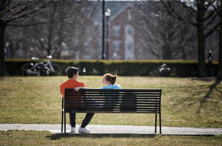 Two people sitting on a bench. 