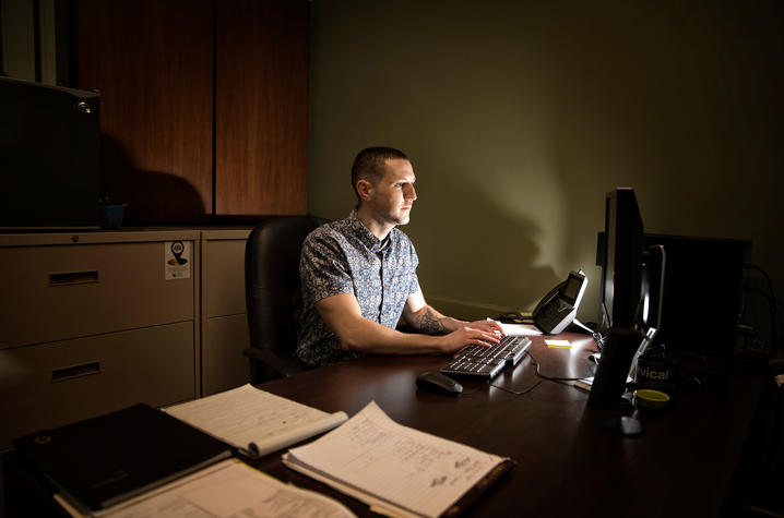 Photo of Trey Cardwell sits at his desk working on a computer Photo by Mark Cornelison | UK Photo