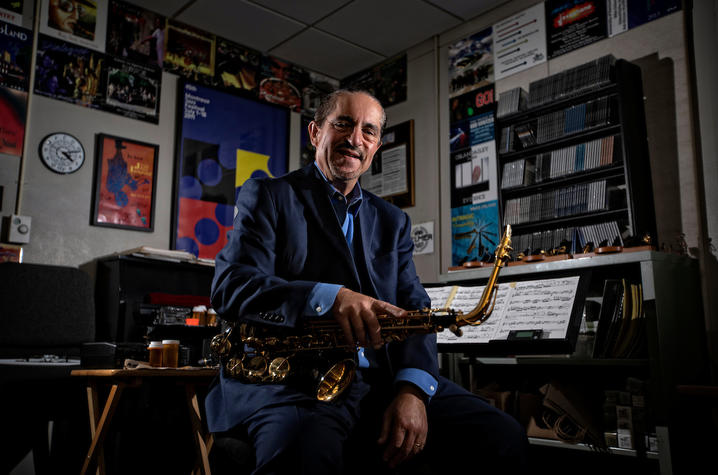 photo of Miles Osland holding his saxophone in his office at UK School of Music