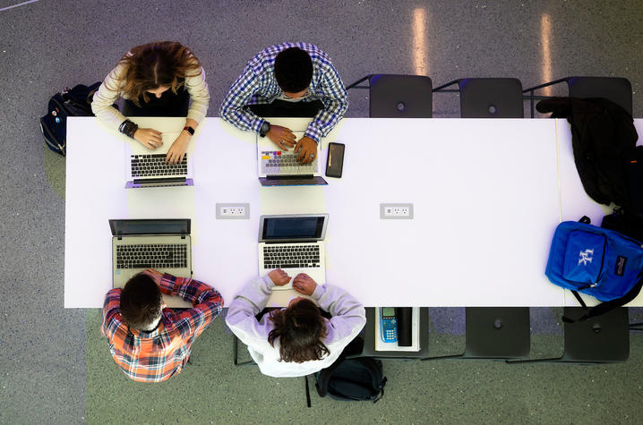 Students seated at table with laptops