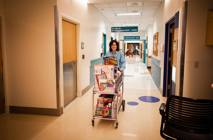 Jennifer Mynear rolls cart of toys through the hospital