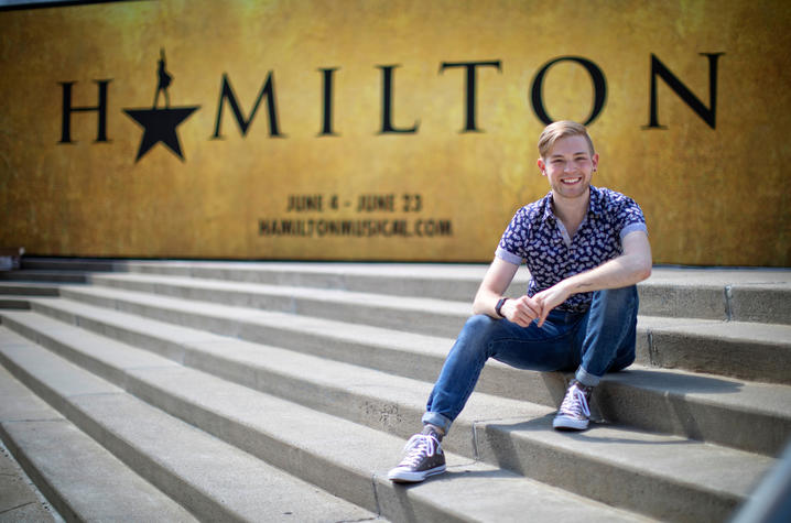 photo of Patrick Garr seated outside The Kentucky Center sign for Hamilton