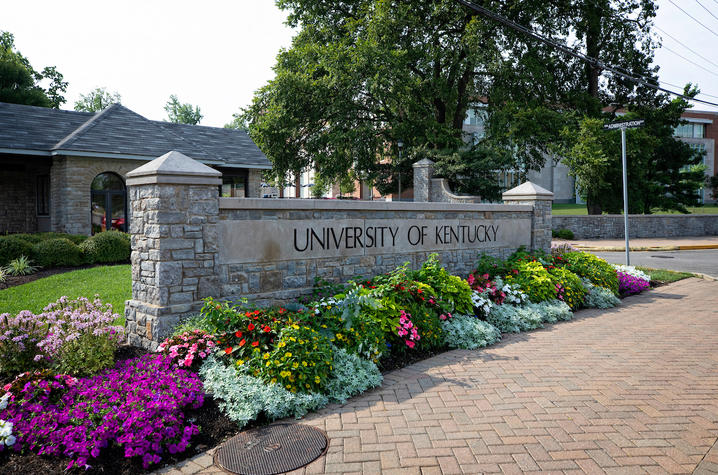 Stone University of Kentucky entrance sign with colorful flowers in front.