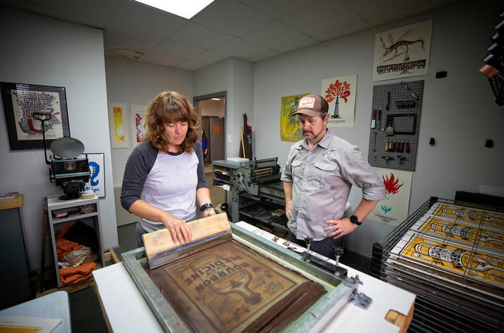 photo of Sara Turner applying ink to print while Brian Turner watches on