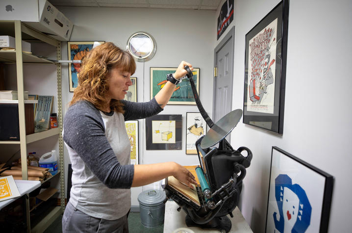 photo of Sara Turner working on a coaster on a small press