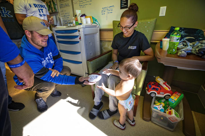 Photo of Sawyer Smith handing football to toddler