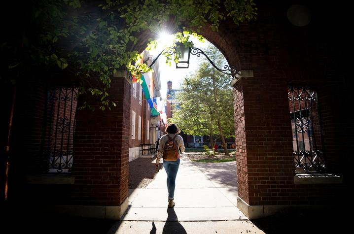 Student walking through archway near UK International Center building