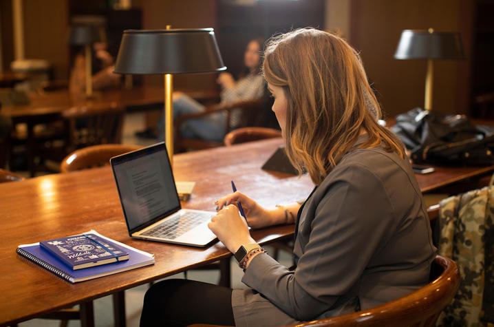 A student sitting, working on a laptop. 