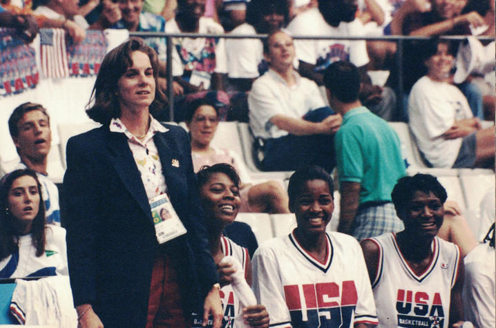 Dr. Ireland stands to the left of the screen with 3 members of the US women's basketball team sitting to her right