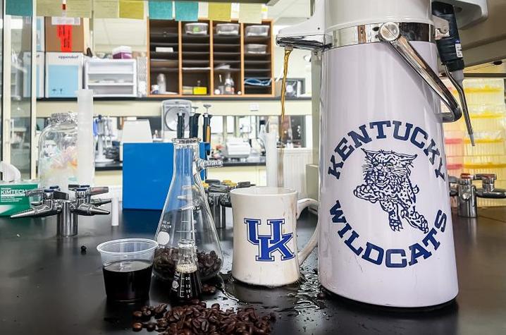 Coffee in beaker in lab next to UK mug and tumbler