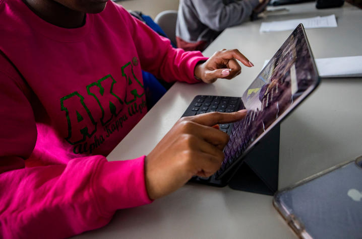 Student in pink AKA shirt works on her iPad.