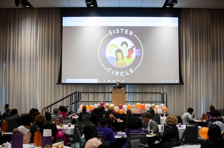 women speaking at podium at last year's Sister Circle Forum. 