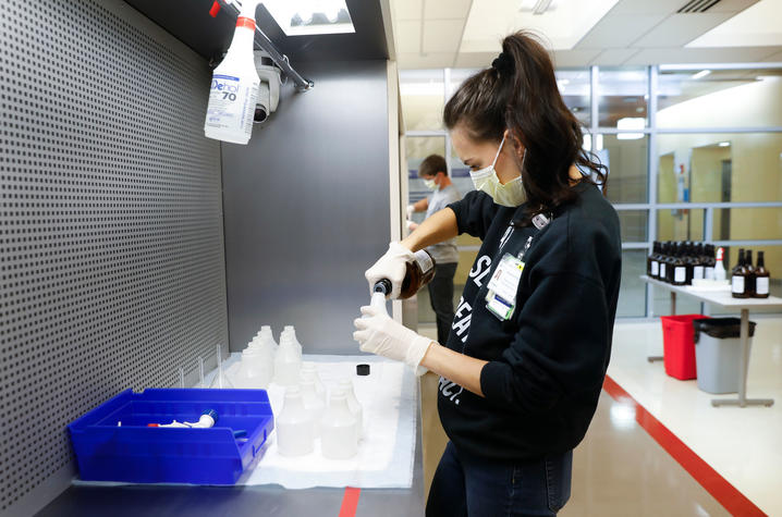 photo of Alex Nilges bottling hand sanitizer in lab