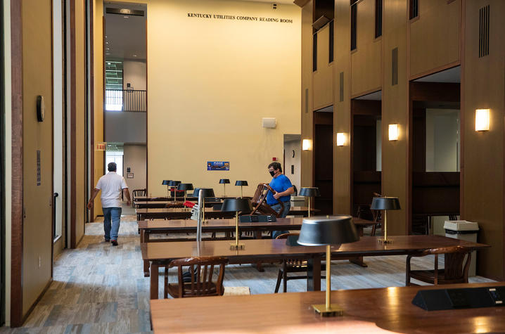 photo of 2 employees removing chairs from Young Library tables