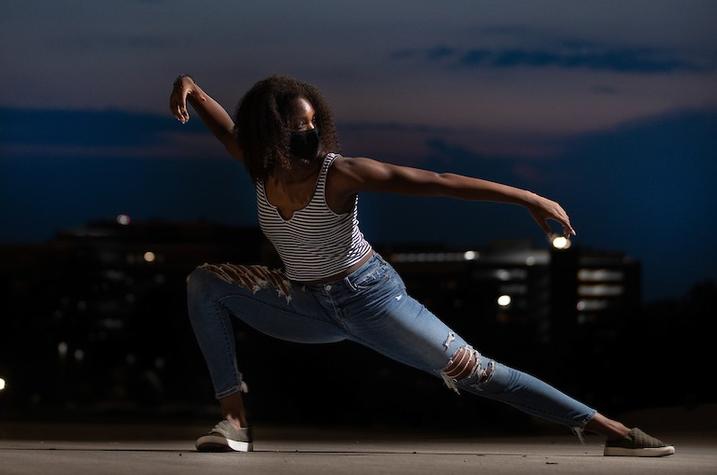 photo of UK dance student peforming with campus landscapte behind her