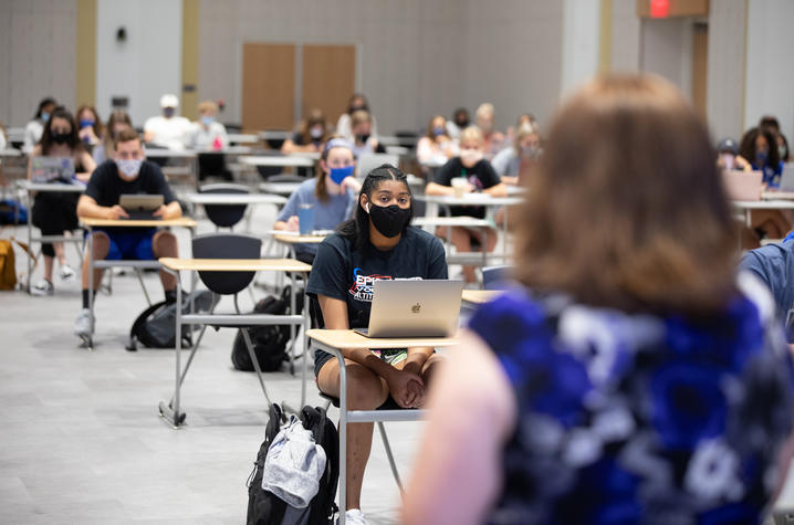 photo of journalism class with students in  masks and back of College of Communication and Information Dean Jennifer Greer's head as she speaks to them.