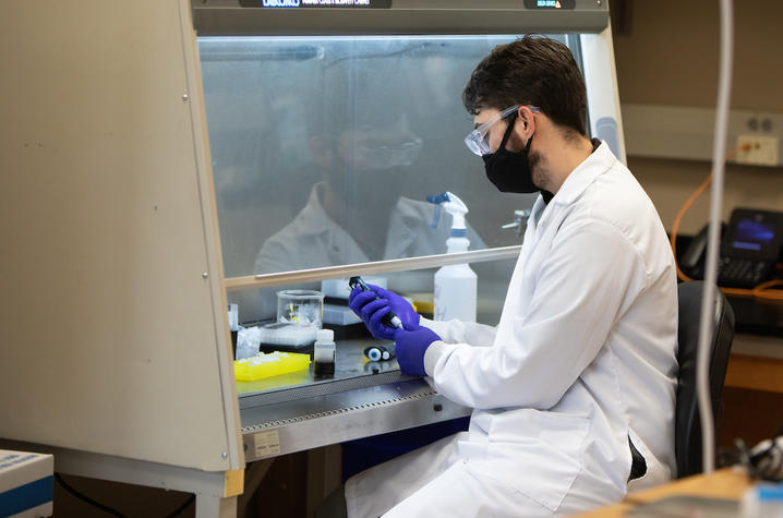 Photo of graduate student Dalton Strike preparing waste water from a residence hall for testing.  