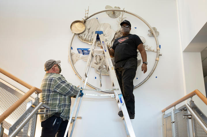 photo of Garry Bibbs on ladder installing "Being Aliver" at Lexington Senior Center