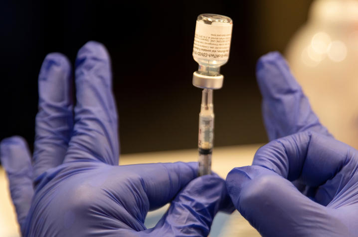 photo of gloved hands holding a syringe and vial of COVID-19 vaccine