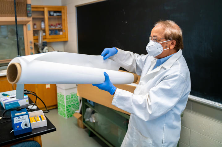 Dibakar Bhattacharyya in the lab with a large sheet of membrane material. Ben Corwin | Research Communications