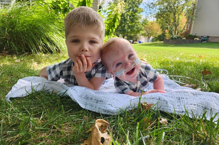 Image of Everett and Nolan lying in the grass on a blanket.