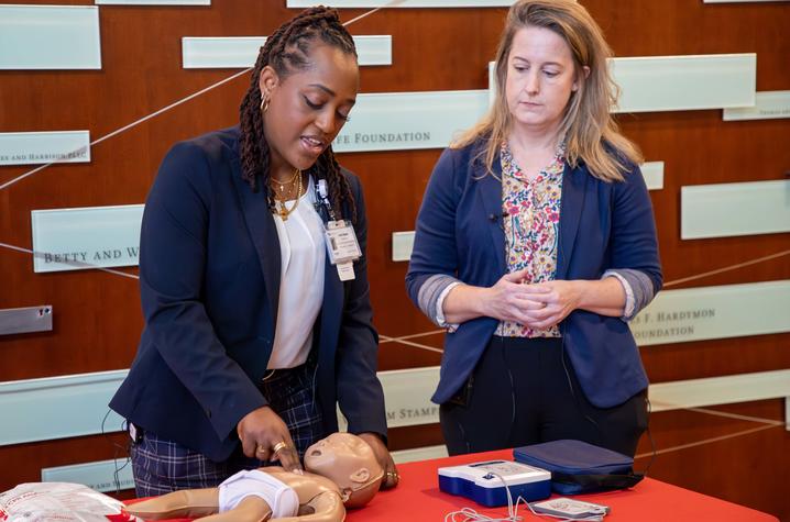 image of two women demonstrating CPR on an infant doll