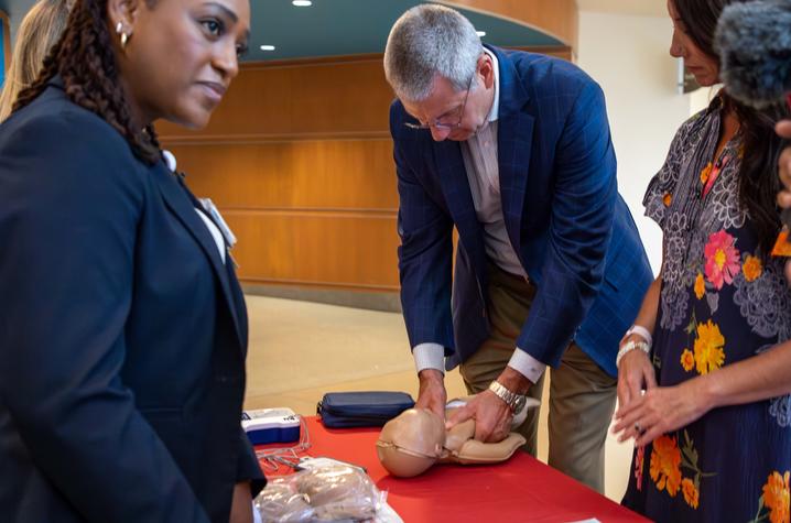 image of man in blue jacket performing CPR on a doll