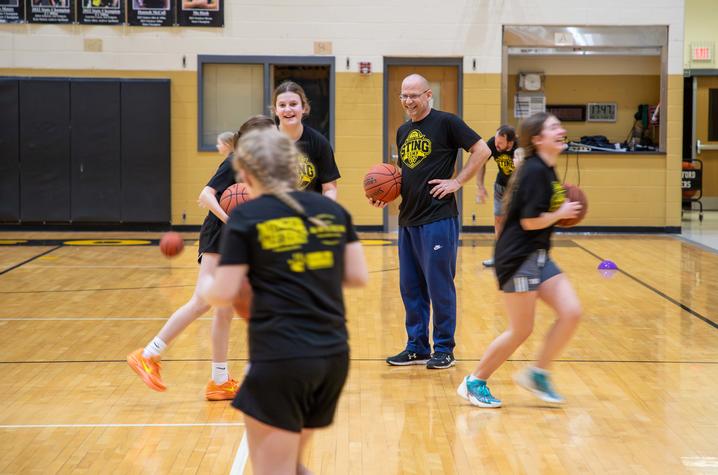 image of Dan Zuber smiling as his players run drills around him on the basketball court