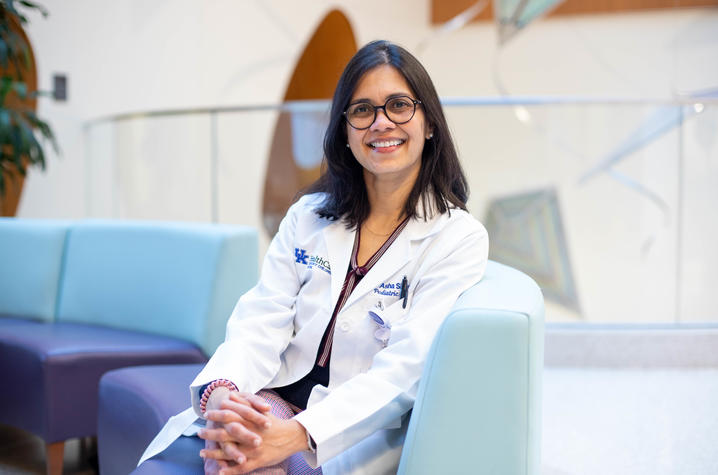 Photo of Dr. Shenoi seated on blue sofa