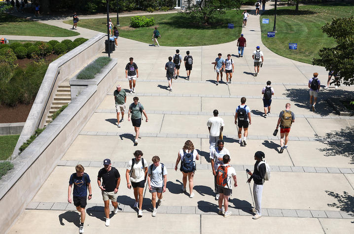 groups of students walking outside on a sidewalk, seen from an elevated viewpoint