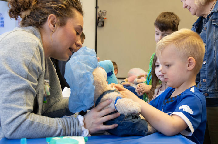 Photo of little boy putting a cast on his teddy bear