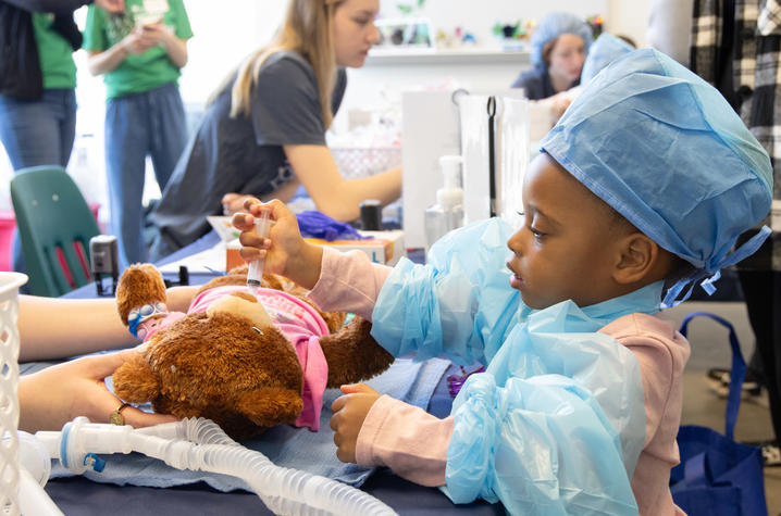 image of little girl in scrubs playing doctor with her bear