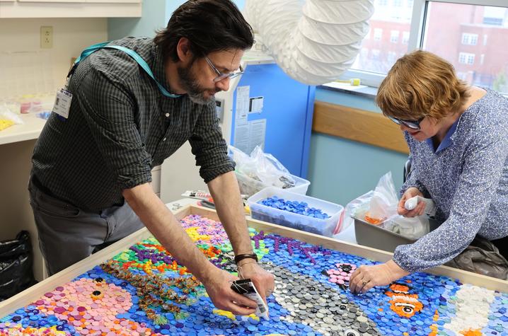 Image of two people glueing plastic to the narwhal art