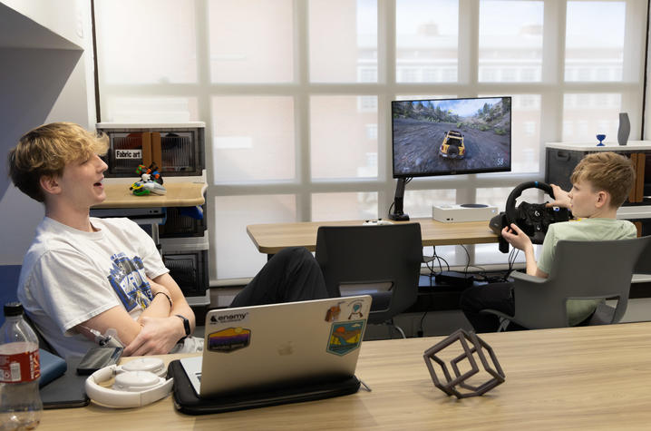 Image of volunteer talking to a patient who is playing a video game