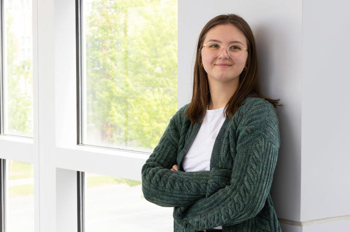 Photo of UK Public Health grad Faith Fursman Young woman with brown hair and glasses leaning against a wall