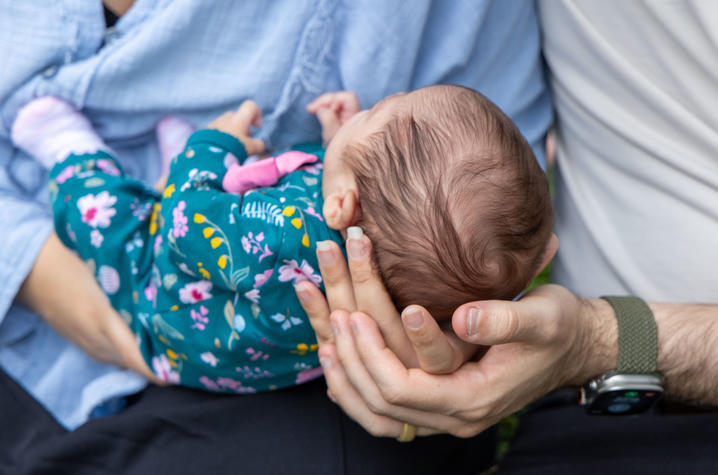 Image of parents hands holding baby's head