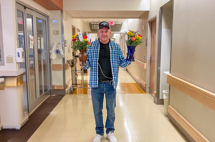 Image of Bobby Patton holding bouquets of flowers in a hospital corridor. 