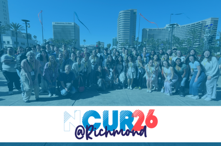 A large group of people pose together outdoors in front of several tall buildings on a sunny day. Streamers or ribbons can be seen in the sky above them. The lower portion of the image contains a white banner with the stylized text “NCUR 26 @ Richmond” in