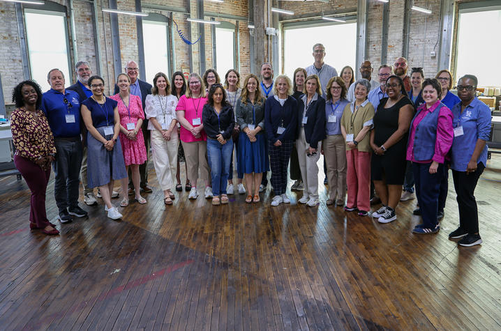 A large group of adults standing in an open office area, posing for a group picture.