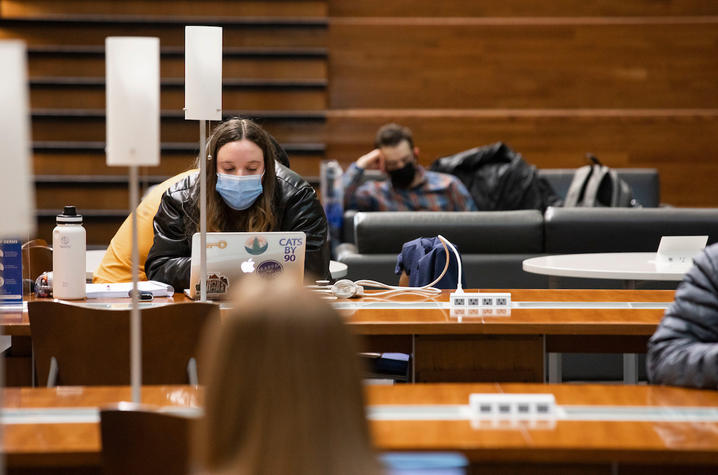 photo of masked student studying in atrium of Gatton College