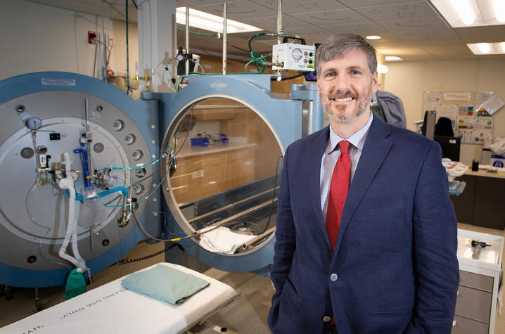 Dr. Kevin Hatton, the division chief of Anesthesiology Critical Care Medicine at UK HealthCare, poses next to the hyperbaric oxygen treatment chamber.