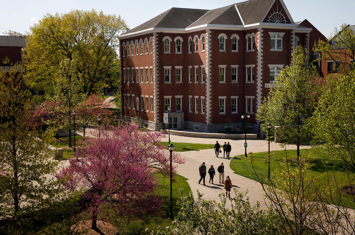 photo of back of Gilis Building with trees blooming and people walking on the sidewalk