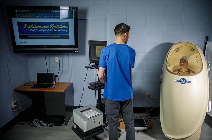 Student (left) standing next to the Bod Pod (right)