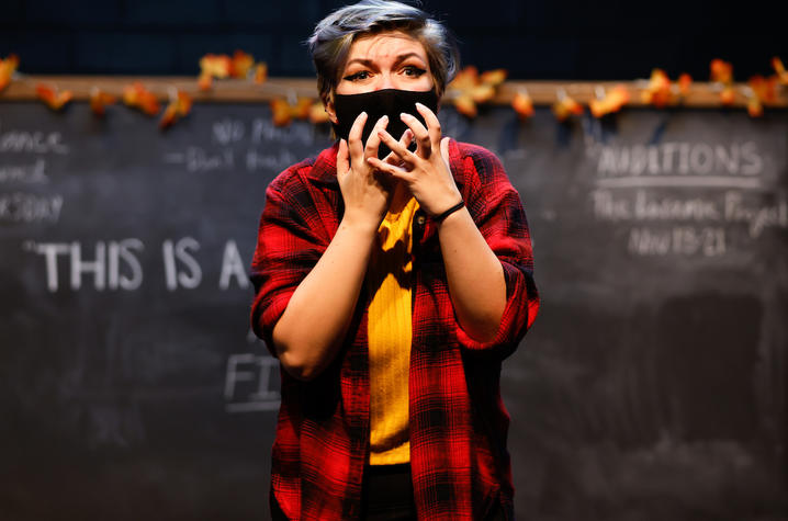 photo of cast member rehearsing UK Theatre's "The Thanksgiving Play" standing in front of chalkboard