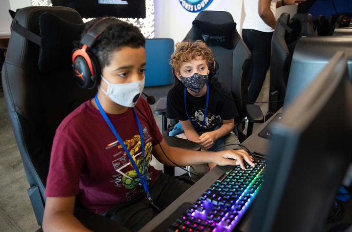 Two kids playing esports on a computer. 