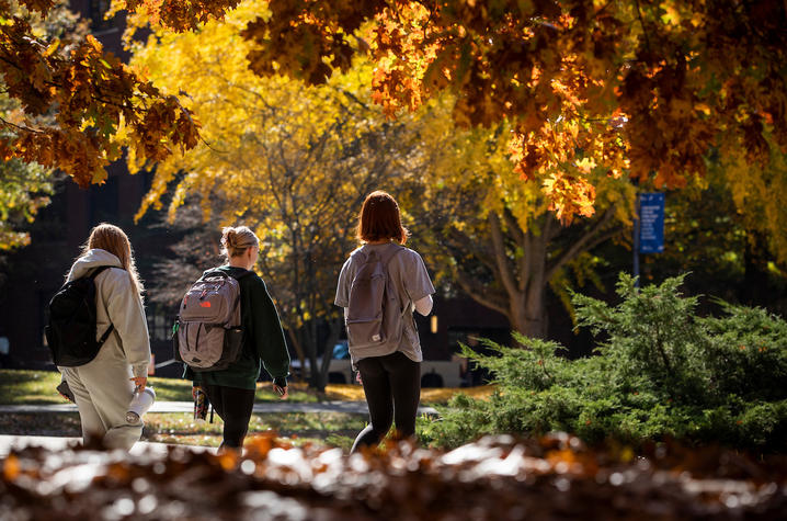 students walking on campus among orange and yellow colored trees