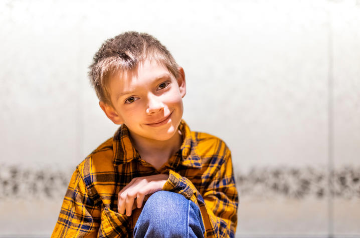 Image of a smiling Lewis Utz who is wearing a yellow plaid shirt and jeans
